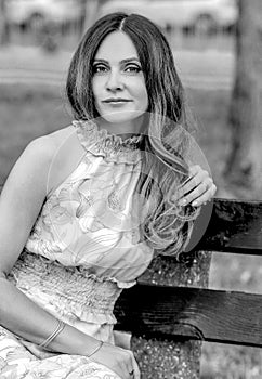 Black and white portrait a Ñaucasian girl sitting on a bench in the park.