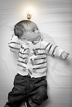 Black and white portrait of baby boy with glowing light bulb overhead
