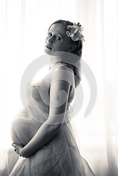 Black and white portrait of beautiful bride holding hands on pregnant belly