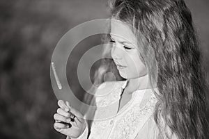 Black and white portrait of a beautiful child with long hair. Childhood in nature. A little girl holds a flower in her