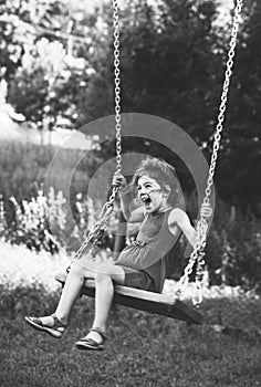 Black and white portrait of Beautiful little girl smiling on swing at summer day, Happy childhood concept. Soft focused