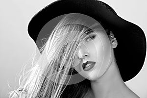 Black and white portrait of beautiful woman in black hat