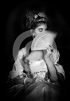 Black and white portrait of beautiful woman dressed in rococo 1700s fashion