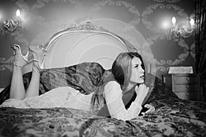 Black and white portrait of beautiful young lady relaxing lying in luxury bed