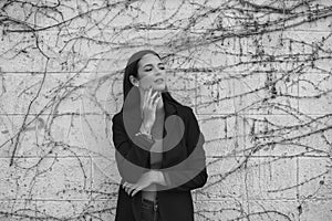 Black and white portrait of beautiful young woman leaning on a wall making different expressions, sad, melancholic, happy,