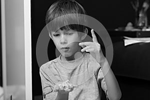 Black and white portrait of a boy casting heap of dice, facial expression of excitement