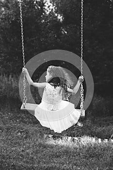 Black and white portrait of cute little girl smiling on swing at summer day, Happy childhood concept