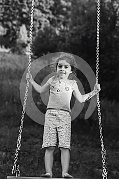 Black and white portrait of Cute little girl smiling on swing at summer day, Happy childhood concept