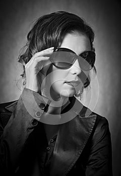 Black and white portrait of edgy woman posing in jacket with large aviator sunglasses