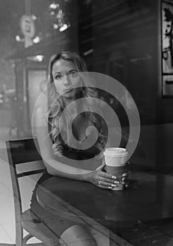 Black and white portrait of elegant blonde woman drinking coffee