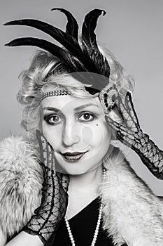 Black and white portrait of a girl in a hat with feathers and lace gloves