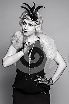 Black and white portrait of a girl in a hat with feathers and lace gloves