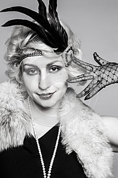 Black and white portrait of a girl in a hat with feathers and lace gloves