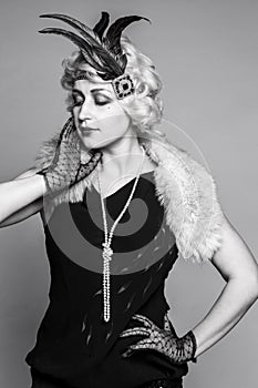 Black and white portrait of a girl in a hat with feathers and lace gloves