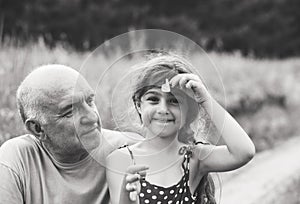 Black and white Portrait of granddad and granddaughter smiling at the park