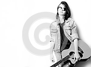 Black and white portrait of handsome teenager in white background holding his guitar