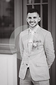 Black and white portrait of handsome young groom in stylish suit outdoors