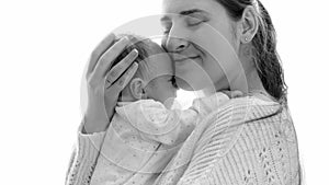 Black and white portrait of happy young mother hugging her little baby son against big window