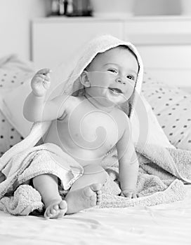 Black and white portrait of laughing toddler boy with towel on head after having bath