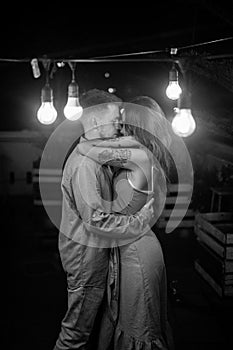 Black and white portrait of loving couple standing in the bar with lanterns