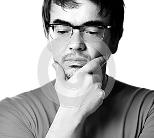 Black and white portrait of man in glasses touching chin and thinking over white background, close-up. Expressing