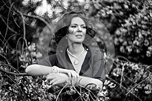 Black and white portrait of a middle-aged brunette in a blue dress next to a blooming linden