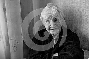 Black and white portrait of an old woman in his house.