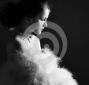 Black and white portrait of pensive kid girl theatre actress in furry clothes with big sleeves and bared shoulders. Side