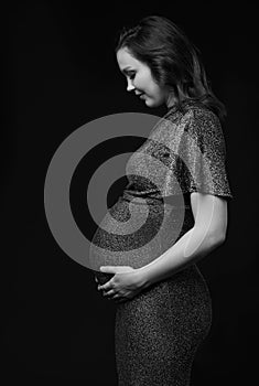 Black and white portrait of pregnant female in sequin dress with hands near pregnant belly