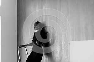 Black-and-white-portrait of pretty african or black american woman touching her thick plait on dark studio background