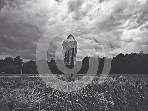 Black and white portrait of sad lonely little young girl standing in grass park with head thrown back in sky