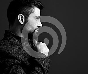 Black and white portrait of self-confident bearded modern businessman holding collar of his stylish tweed jacket