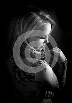 Black and white portrait of sensual blonde woman posing in dramatic natural light, wearing a floral top