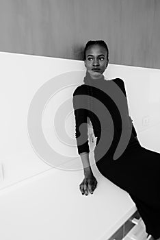 Black-and-white portrait of a serious african or black american woman standing over gray background and looking away