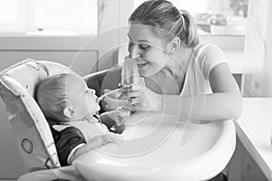 Black and white portrait of smiling mother feeding her baby in h