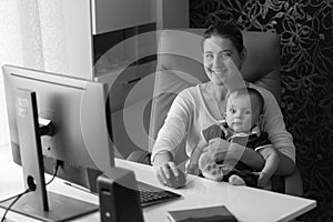 Black and white portrait of smiling mother sitting in office chair with her baby