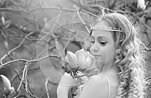 Black-white portrait of stunning young beauty blonde with jewelry for hair in the garden where magnolia trees bloom.  Jewelry for