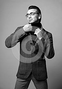 Black and white portrait of stylish businessman in jeans, checkered plaid jacket and black scarf standing looking aside