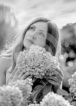 Black and white portrait a sweet girl with stunning curls in a hydrangea garden.