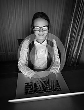 Black and white portrait of teenage girl in eyeglasses sitting a