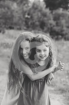 Black and white portrait of Two Happy little girls laughing and hugging at the summer park