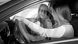 Black and white portrait of two laughing girls singing and smiling hile driving a car photo