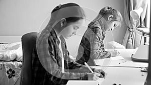 Black and white portrait of two teenage girls doing homework in bedroom