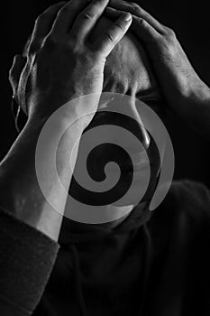 Black and white portrait of a young bald man who with his hands on his head looks desperate