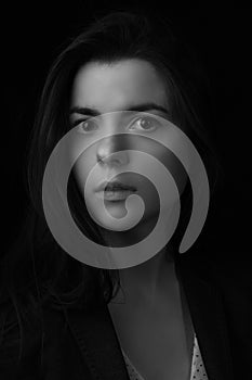 Black and white portrait of young brunette woman in a studio on a black background