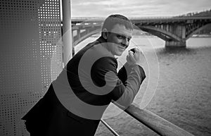 Black and white portrait of young businessman posing on balcony