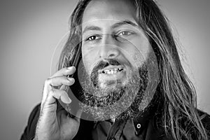 Black and white portrait of a young middle eastern businessman with beard and long hair while having a conversation on the mobile