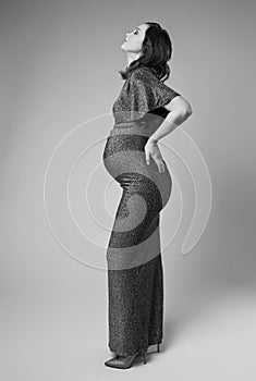Black and white portrait of young pregnant female in grey sequin dress