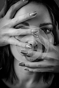 Black and white portrait of a young woman with her face covered with hands, concept for showing the anxieties and fears of women