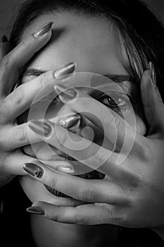 Black and white portrait of a young woman with her face covered with hands, concept for showing the anxieties and fears of women